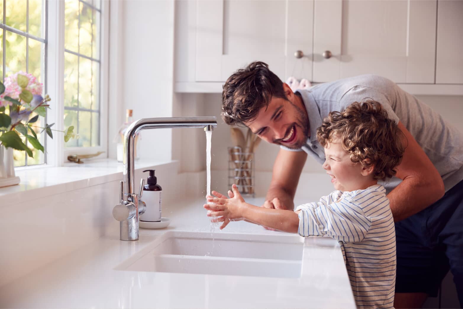 Young boy and father washing hands at sink