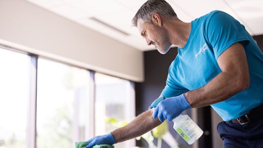 ServiceMaster Clean® technician with a blue uniform and a spray bottle