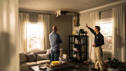 Two men looking at water damage in ceiling of house
