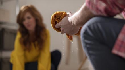 hands wringing out rag with woman in background