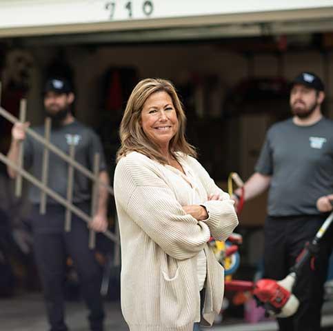 Woman in front of garage with junk removal team